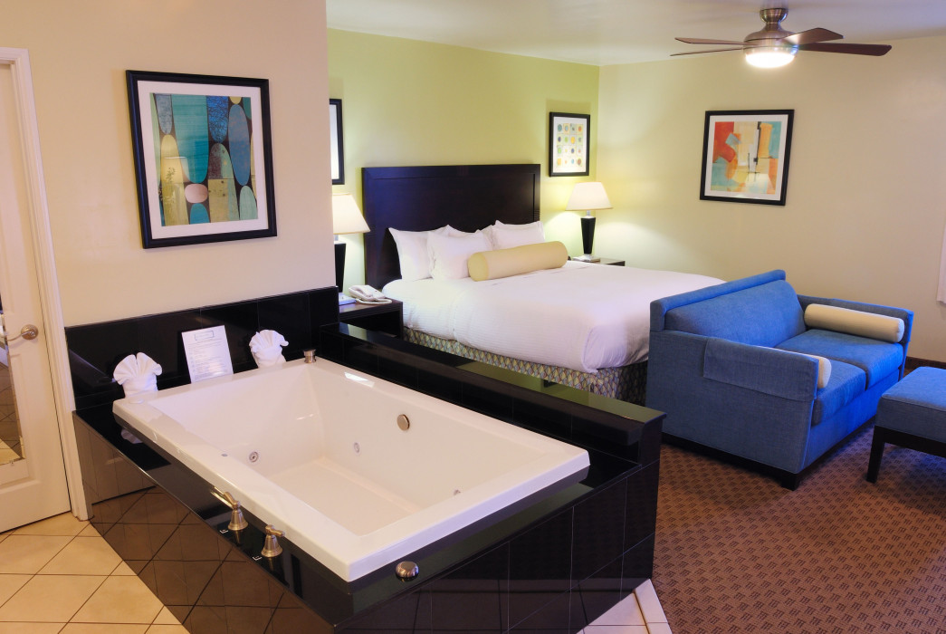 A hotel room with a large bed, a sofa, and a jacuzzi tub