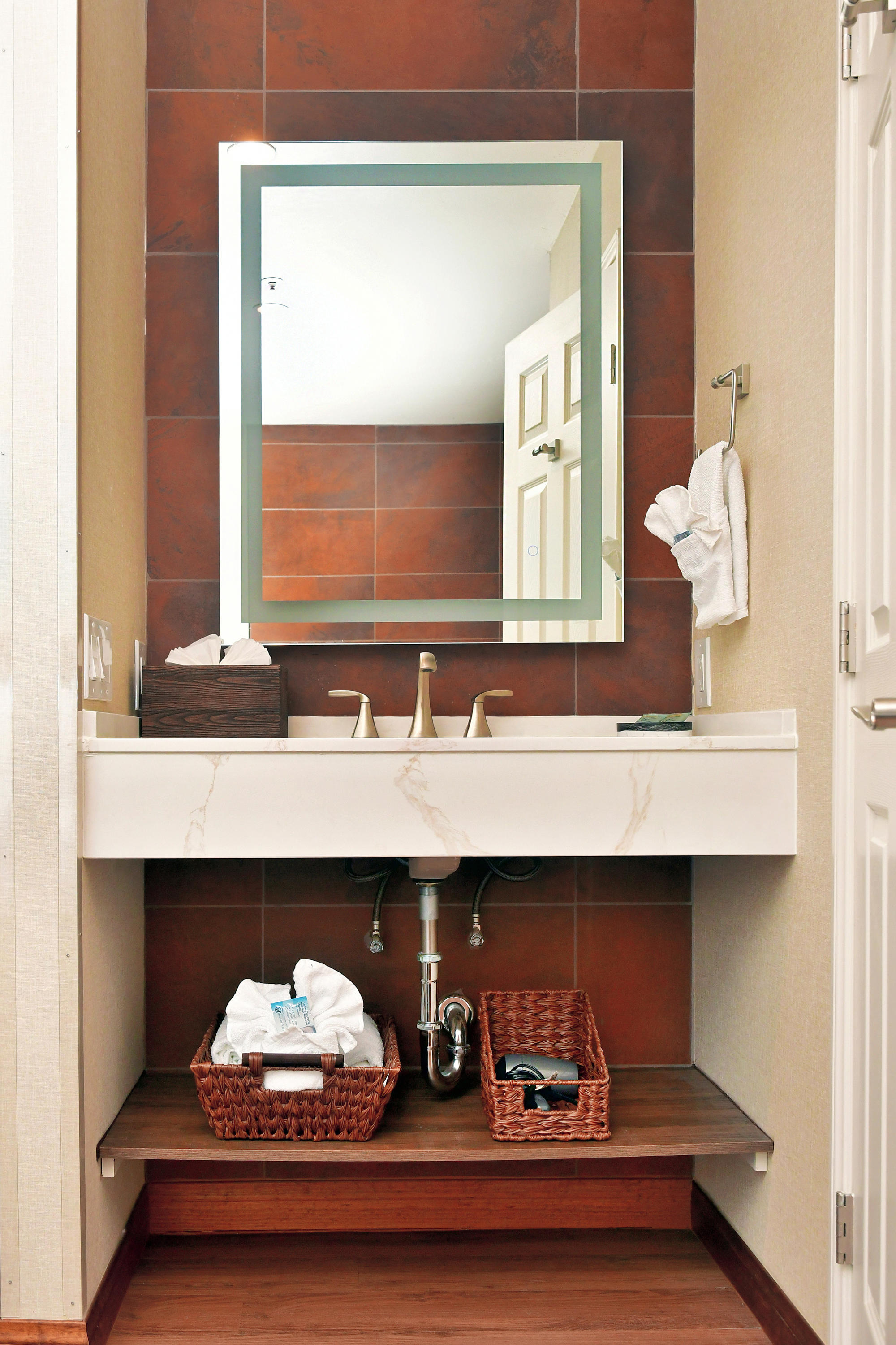 A bathroom sink with a mirror and tiled wall