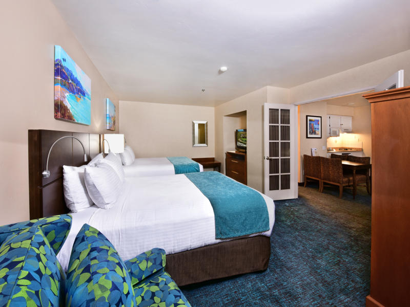 A wide view of a hotel room with two beds, a sofa, and a desk.
