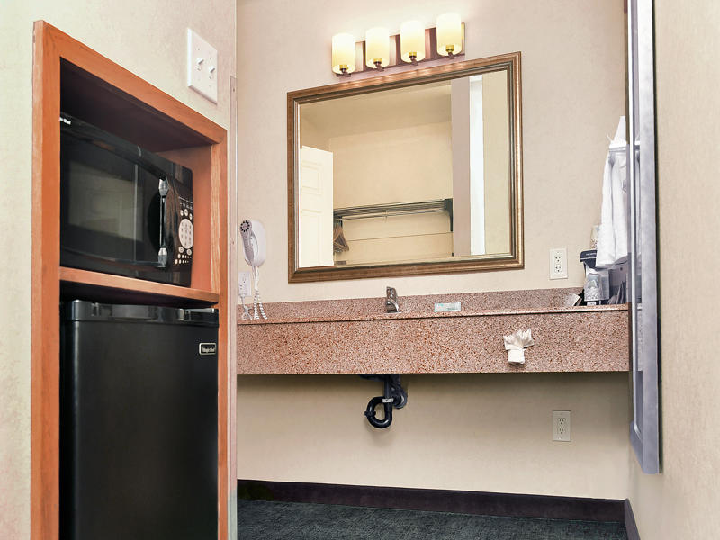 A bathroom with a granite sink, mirror, and amenities.